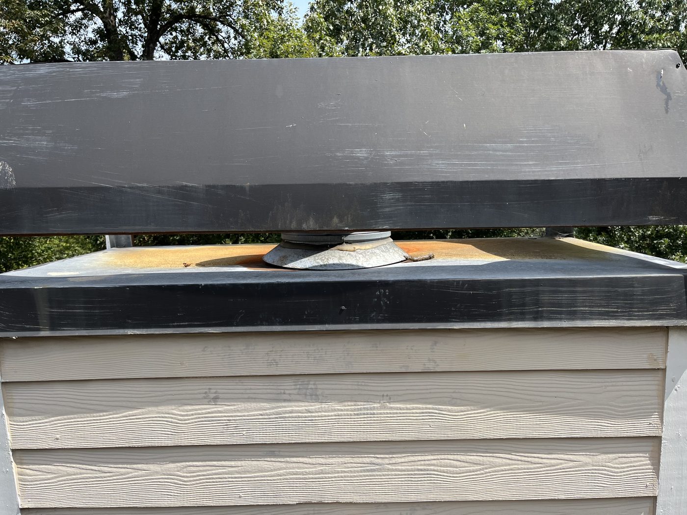 Rusted rain pan on chimney cap